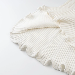 Close-up of white ribbed knit fabric featuring delicate ruffled hem and soft texture