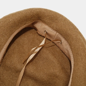 Detail of adjustable drawstring inside camel wool beret showing metal eyelet craftsmanship