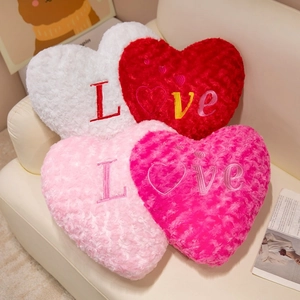 Set of heart-shaped plush pillows with rose texture and Love embroidery on sofa