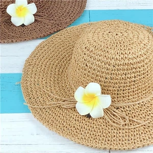 Close-up of woven straw hats featuring rustic rope trim and white Plumeria floral details
