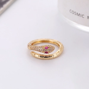 Gold snake ring with sparkling white crystals and pink gemstone eyes on white backdrop