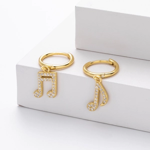 Macro detail of gold-plated music note earrings with pavé white zircon stones