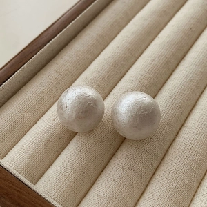 Minimalist grey cotton pearl stud earrings with textured matte finish on beige velvet