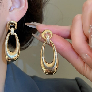 Close-up of gold oval drop earrings with micro-pave diamond detail on the link