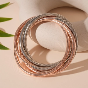 Detail von mehrlagigen Schlangenketten-Armbändern in Roségold und Silber