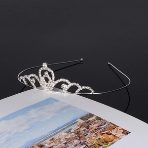 Close-up of a silver rhinestone crown with wave patterns on an open book background