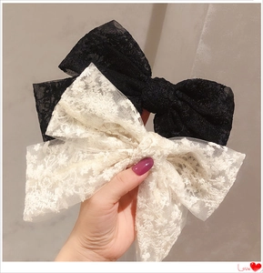 Detail showing high-quality black and white floral lace bow hair clips with long ribbons