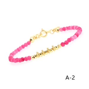 Detailed close-up of rose red chalcedony beads and gold plated metal accents on the bracelet