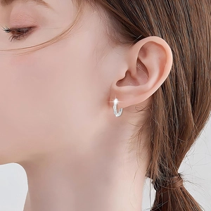 Macro detail of S925 sterling silver hoop earrings with sparkling zircon inlay on earlobe