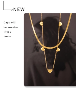 Detail of layered gold snake chain and delicate necklace with five 3D heart charms