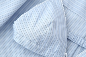 Detailed macro view of blue striped fabric with delicate lace trim on crop top