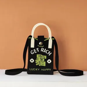 Detail of a woven mini bag featuring GET RICH text and lucky clover knit patterns