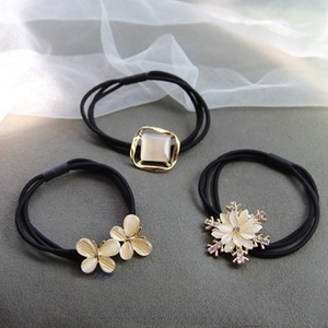 Detail of three black elastic hair ties featuring rhinestone, butterfly, and snowflake charms