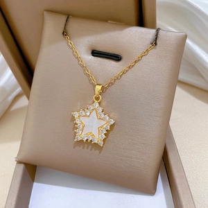 Close-up of golden star necklace with shell inlay and pavé crystals in a gift box