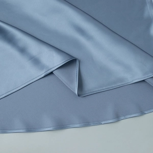 Detail of light blue satin fabric showing smooth texture and precision hem stitching
