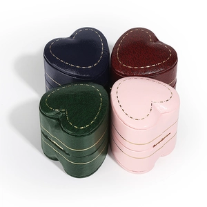 Mini heart-shaped jewelry boxes in four colors with gold stitching on white background