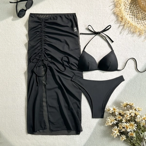 Flat lay of a black three-piece bikini set with a mesh drawstring beach skirt