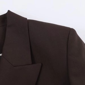 Détail d'un blazer marron foncé présentant les revers et les coutures de l'épaule