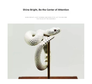Detail of silver rattlesnake ring with scale texture and red crystal eyes on a stand