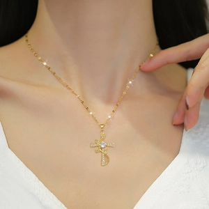 Close-up of a gold cross necklace with crystal-encrusted rose design worn by a model