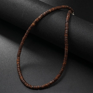 Detail of vintage coconut shell and turquoise beaded necklace on a black display stand
