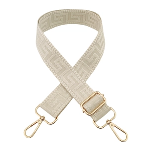 Detail of adjustable geometric Greek key pattern bag strap with gold metal buckles