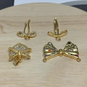 Macro detail of four gold bow pendants with clear and colorful zircon stone inlay