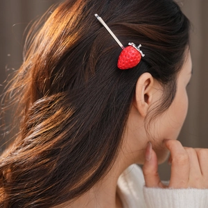 Primo piano di un fermaglio per capelli a fragola rossa su lunghi capelli castani