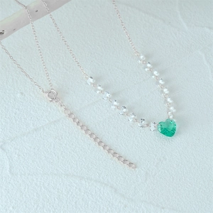 Close-up of silver necklace featuring a green heart pendant and adjustable link chain