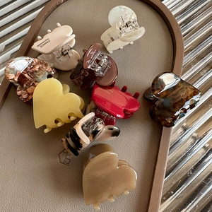 Handmade acetate heart claw clips in multiple colors on a textured tray