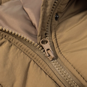 Macro shot of matching khaki zipper and smooth fabric texture of a long puffer coat