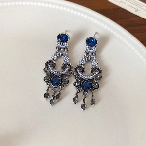 Detail of vintage silver earrings with blue stones, grey rhinestones and pearl tassels
