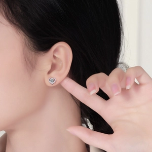Side view of elegant heart-shaped silver moissanite stud earrings on a female model