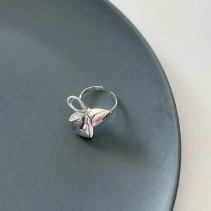 Detailed view of silver S925 bow-shaped open ring on a textured grey background plate