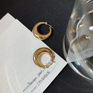Makroaufnahme dicker goldener C-förmiger Creolen mit hochglanzpoliertem Metall-Finish