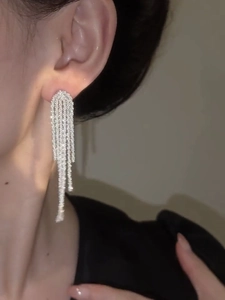 Close-up of shimmering silver tassel earrings worn by a model in soft natural light