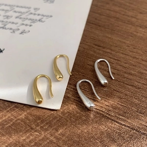 Minimalist gold and silver teardrop hook earrings with polished mirror finish on wood