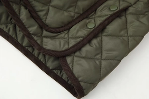 Détail de la veste matelassée vert armée avec bordure en velours côtelé et boutons pression