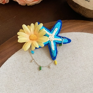 Close-up of floral starfish hair clip on wooden tray with rustic linen background