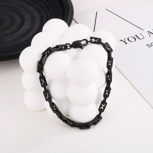 Dettaglio macro del bracciale a catena a maglie quadrate nere su cubo espositivo