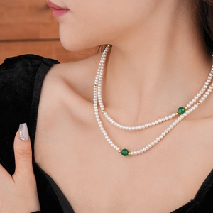Detail view of double-layered faux pearl necklace with green agate beads and gold accents