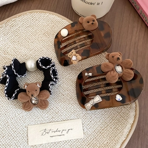 Detail of fabric scrunchie with acrylic pearl bear and tortoiseshell hair clips on mat