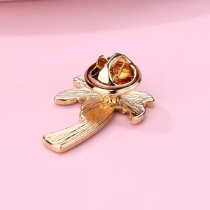 Macro detail of a golden palm tree brooch showing the metal texture and pin back