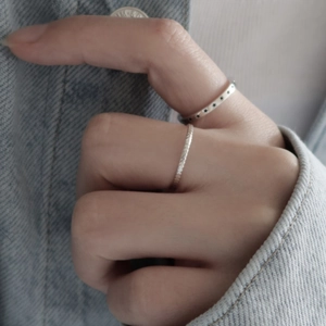 Detail of 925 sterling silver star ring and woven band worn on hand over denim
