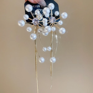 Detailed view of long starburst earrings with white pearls and 925 silver needles