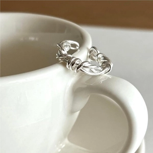 S925 sterling silver twisted knot ring hanging on a white ceramic cup edge
