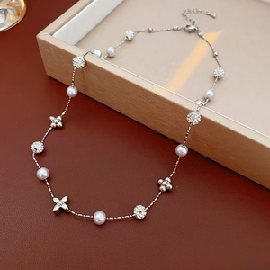 Close-up of gold-plated flower pearl necklace with zircon and four-leaf clover details