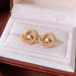 Vintage style gold twist knot earrings with central pearl in a beige velvet jewelry box