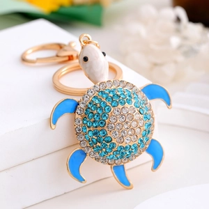 Detailed close-up of a golden turtle keychain with blue opal shell and sparkling crystals