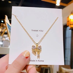 Collier élégant doré avec pendentif nœud en zircone sur une carte blanche